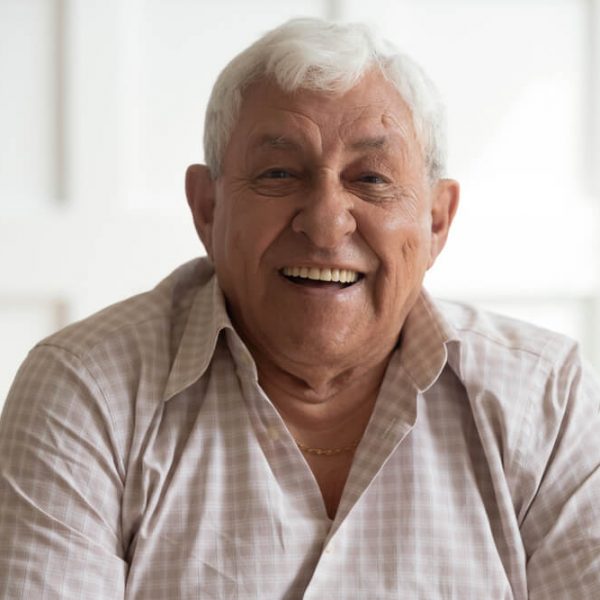 an older man smiling while sitting on the couch