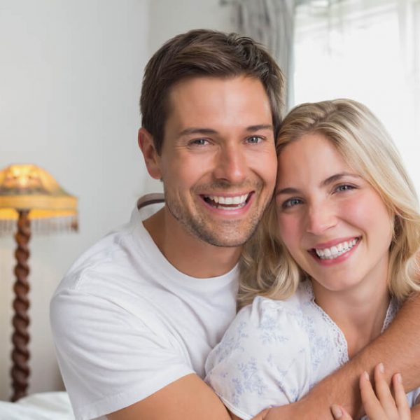 a young couple both smiling while embracing each other