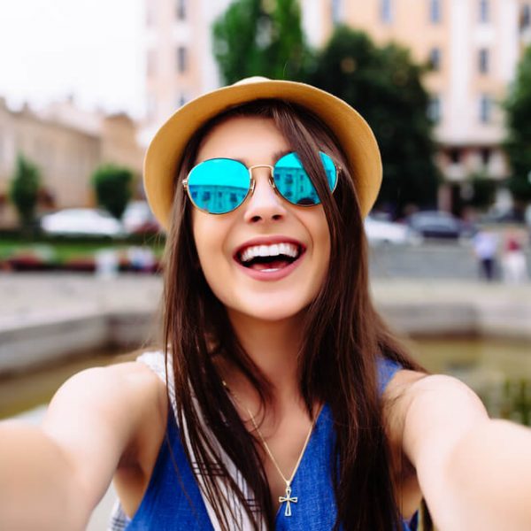 a young woman taking a fun selfie while outside smiling
