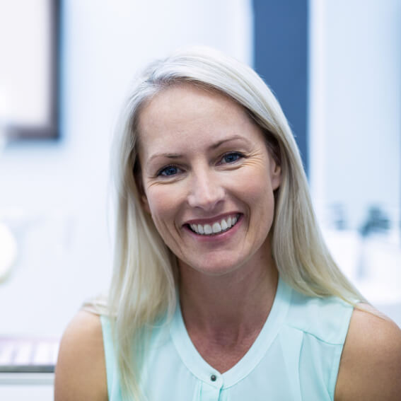 A middle aged woman smiling while at the dentist's office