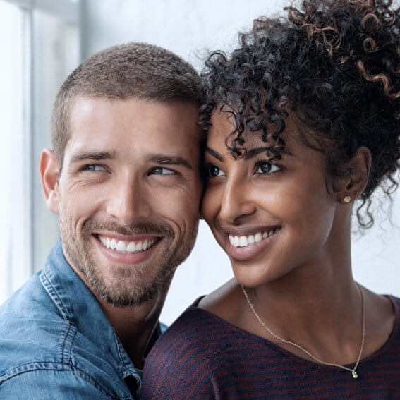 A young couple looking out the window, both smiling